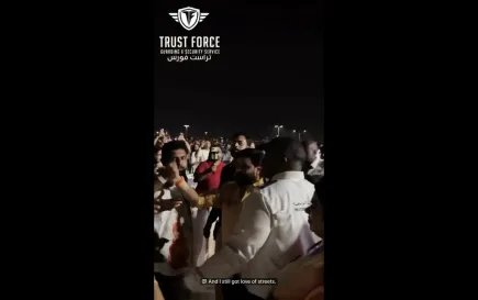 Trust Force security guard in white uniform managing crowd movement around a celebrity surrounded by fans at a night event in Doha, Qatar — professional event security and close protection services by Trust Force Guarding & Security Services