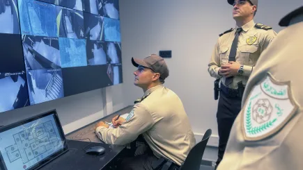 TrustForce security officers in uniform monitoring a multi-screen CCTV surveillance system during the National Protection Officer training programme in Qatar, demonstrating operational readiness and technical security skills.